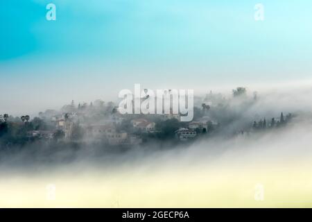 villaggio rurale di montagna in nebbia. Fotografato sul Monte Carmelo, Israele Foto Stock