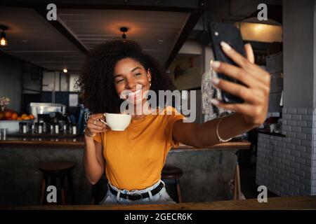 Bella gara mista che prende selfie con caffè caldo rilassante in un ristorante alla moda Foto Stock