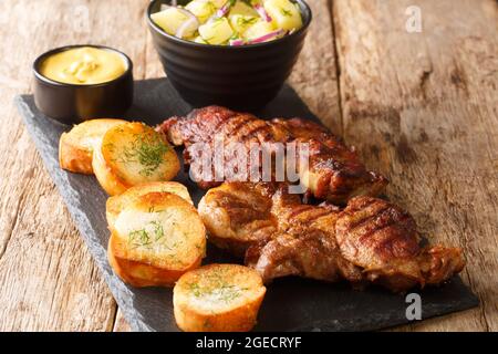 Schwenkbraten maiale tedesco grigliato collo di costolette con insalata di patate, senape e toast da vicino nella tavola di ardesia sul tavolo. Orizzontale Foto Stock