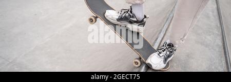 vista parziale dell'uomo in scarpe sportive a cavallo skateboard sulla rampa di skate, banner Foto Stock