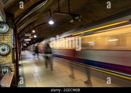 Persone che passano davanti a un treno in movimento alla stazione della metropolitana di Baker Street a Londra, Inghilterra Regno Unito Foto Stock