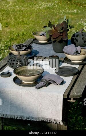 Tavolo rustico all'aperto in giardino con stoviglie in ceramica artigianale vuote Foto Stock