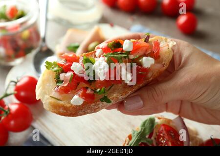 La mano femminile tiene la bruschetta, il primo piano e la messa a fuoco selettiva Foto Stock