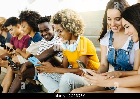 Gruppo multietnico di giovani amici che usano il cellulare Foto Stock