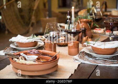 La tavola è allestita per cena con prodotti tipici italiani, olive, cipolla in olio, vino rosso Foto Stock