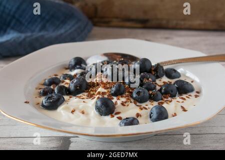 Una ciotola con Skyr, mirtilli freschi e semi di lino su tavola rustica e in legno Foto Stock