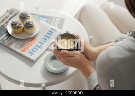 Giovane donna con tazza di caffè a casa, primo piano Foto Stock