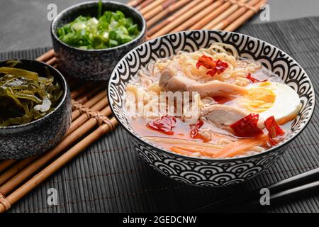 Gustosa zuppa cinese con pollo in ciotola e alghe a sfondo scuro Foto Stock