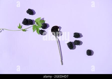 Cucchiaio con gustosa marmellata di more e frutti di bosco su sfondo colorato Foto Stock