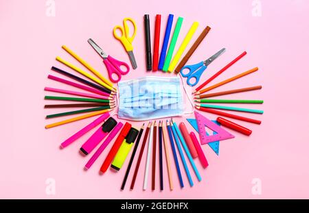 Set di cancelleria e maschera medica su sfondo a colori Foto Stock