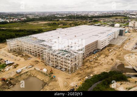 Vista aerea di un grande magazzino di un centro di distribuzione alla periferia di una grande città in costruzione e in costruzione Foto Stock