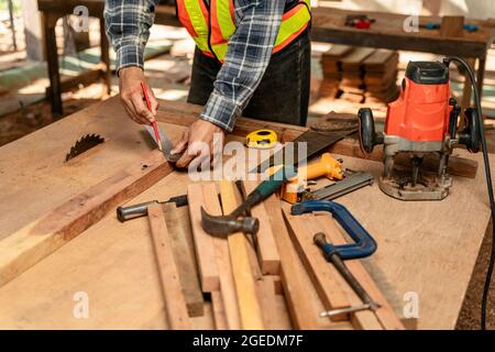 primo piano mano di carpentiere che lavora su macchine per la lavorazione del legno in falegnameria. carpentiere lavora su cantiere Foto Stock