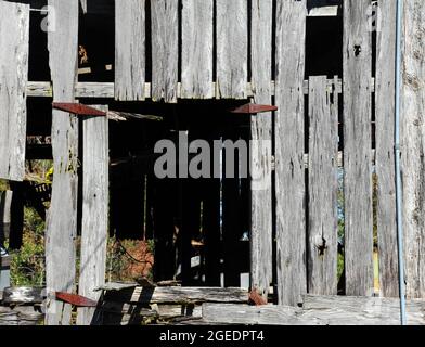 Loft in Derelict Barn manca la sua porta. Le cerniere arrugginite segnano dove sarebbe stato lo sportello. L'apertura ha la forma di un blocco. Foto Stock