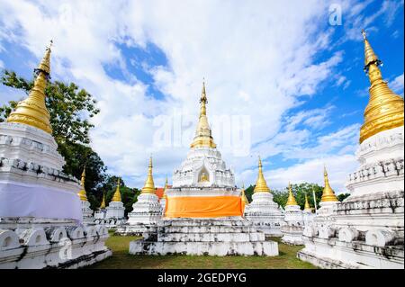 Molte pagode nel tempio thailandese con cielo blu nuvoloso Foto Stock