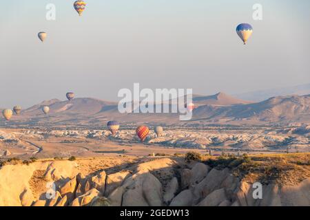 Molti palloncini d'aria calda nel cielo sopra una valle in Cappadocia, Nevsehir, Turchia in una bella giornata estiva. Fuoco morbido Foto Stock