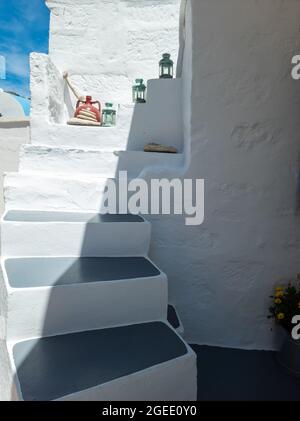 Edificio dipinto di bianco, vuoto stretto mezzo soleggiato pietra lanterne decorative su. Architettura greca tradizionale vecchia struttura a Kimolos isola summe Foto Stock