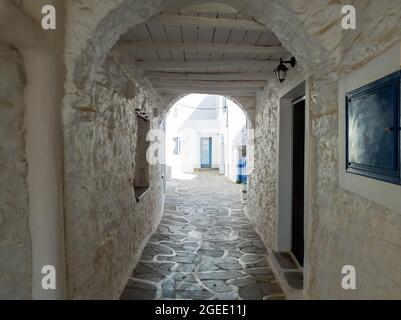 CYCLADES destinazione Grecia Kythnos isola Chora villaggio. Edifici antichi imbiancati di bianco architettura greca, stoa Arch riparo in legno copre vuoto stretto c Foto Stock