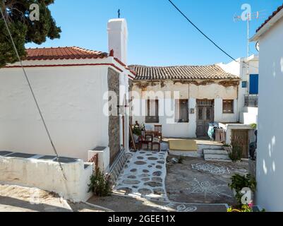 Vecchia casa arrugginita tradizionale tetto piastrellato accanto alle Cicladi architettura greco-ortodossa cristiana Cappella a Kythnos isola, MESSARIA città Grecia. Asfalto Foto Stock