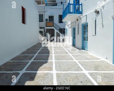 Tradizionale architettura greca di edifici in pietra imbiancati a calce chiuda negozi vuota strada acciottolata. Mykonos isola Chora città, Cicladi Grecia. S Foto Stock