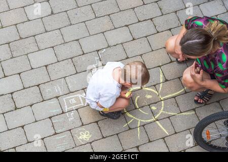 Vista dall'alto sul disegno di bambini su lastre di pavimentazione e donna che lo guarda. Svezia. Foto Stock