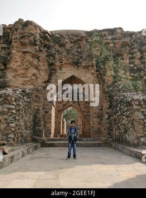 Delhi, India - 18 Febbraio 2018, Boy in piedi tra l'arco, vicino al Qutub Minar Complex, il più alto minareto di mattone del mondo, Nuova Delhi. India Foto Stock