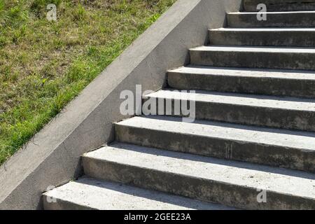 Architettura astratta con scale di cemento vuote e erba verde su un pendio Foto Stock