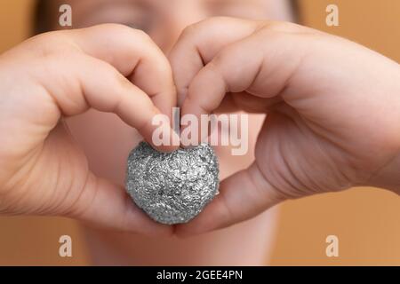 Giovane ragazzo che tiene un foglio di alluminio a forma di sfera Foto Stock