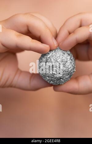 Giovane ragazzo che tiene un foglio di alluminio a forma di sfera Foto Stock