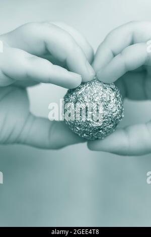 Giovane ragazzo che tiene un foglio di alluminio a forma di sfera Foto Stock