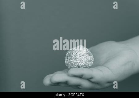 Giovane ragazzo che tiene un foglio di alluminio a forma di sfera Foto Stock