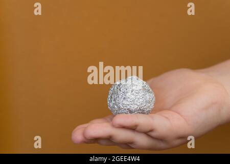 Giovane ragazzo che tiene un foglio di alluminio a forma di sfera Foto Stock