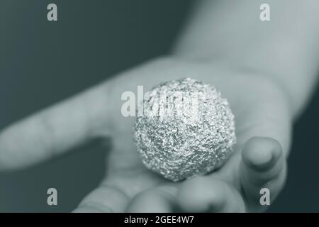 Giovane ragazzo che tiene un foglio di alluminio a forma di sfera Foto Stock