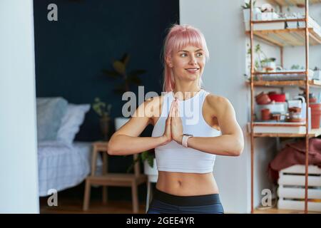 Il praticante di yoga fa mudra di namaste dalle mani durante l'addestramento domestico sul balcone Foto Stock