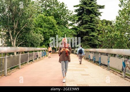 Stock foto di bella donna musulmana che cammina e guarda il suo cellulare. Indossa un Hiyab Foto Stock