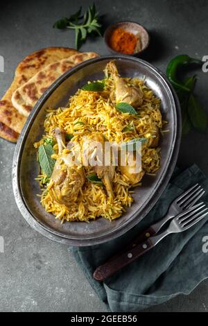 Cibo indiano o pakistano. Biriany di riso chiken Biryani con erbe di menta e pane naan su sfondo grigio Foto Stock