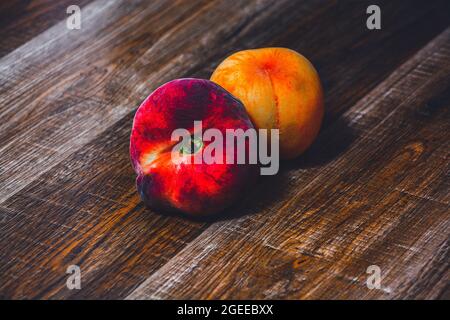 Pesca con foglia. Frutta fresca di pesca d'arancia succosa di pesco su legno taglio rustico tavola. Primo piano del raccolto di pesche in chiave scura Foto Stock