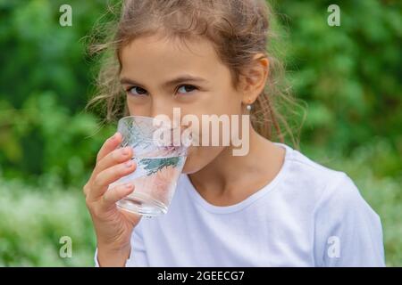 Il bambino beve acqua da un bicchiere. Focus.Nature selettivo Foto Stock