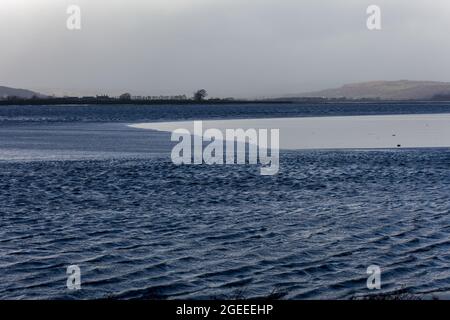 Il bore di Arnside, un'onda stupefacente che viaggia a monte nell'estuario del Kent in Cumbria sulle maree primaverili più alte, visto da Sandside Foto Stock