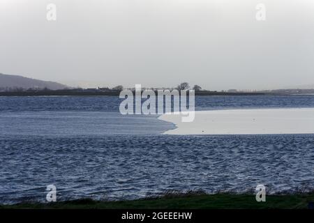 Il bore di Arnside, un'onda stupefacente che viaggia a monte nell'estuario del Kent in Cumbria sulle maree primaverili più alte, visto da Sandside Foto Stock