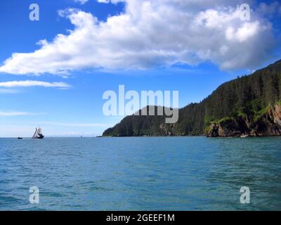 Le barche da pesca fanno il loro commercio sul suono del Principe William e sulla baia di Valdez, Alasksa. Chugach Mountains abbraccia la costa rocciosa. Foto Stock