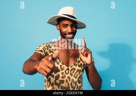 Giovane uomo allegro che balla in studio e guarda la macchina fotografica Foto Stock