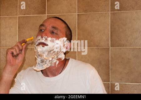 Vaduz, Liechtenstein 1 luglio 2021 un uomo con una barba grande sta in piedi in un bagno con il suo rasoio Foto Stock