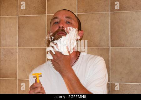 Vaduz, Liechtenstein 1 luglio 2021 un uomo con una barba grande sta in piedi in un bagno con il suo rasoio Foto Stock