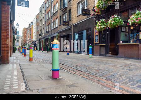 Londra, Regno Unito. 17 agosto 2021. I pilastri di Floral Street, Covent Garden fanno parte di un'installazione d'arte "niente può separarci" dell'artista londinese Lakwena. Bandiere sulla trafficata King Street e Henrietta Street blasonate con messaggi positivi come Londra celebra l'inizio dell'estate e emerge dall'ultima fase di Lockdown e Floral Street con paletti colorati dipinti a mano. Credit: SOPA Images Limited/Alamy Live News Foto Stock