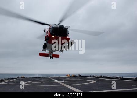 Coast Guard MH-60J Jayhawk si prepara a atterrare sul ponte di volo a bordo della Cutter Munro Coast Guard nell'Oceano Pacifico, 25 luglio 2021. La Cutter Munro della Guardia Costiera è destinata ad andare avanti nell'Oceano Pacifico occidentale per rafforzare le alleanze e le partnership e migliorare la governance e la sicurezza marittima nella regione. (STATI UNITI Foto del corpo marino di Sgt. Kevin G. Rivas) Foto Stock