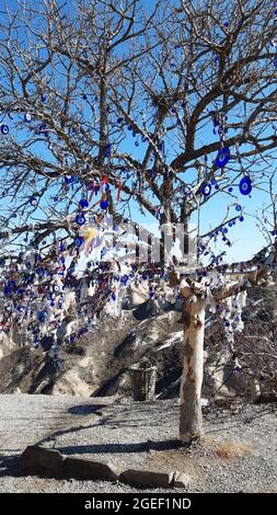 Colpo verticale di un albero secco appeso con perle malvagie dell'occhio con cielo blu sullo sfondo, Cappadocia Foto Stock