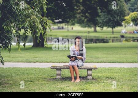Il giovane caucasico legge la Bibbia mentre si siede su una panchina Foto Stock