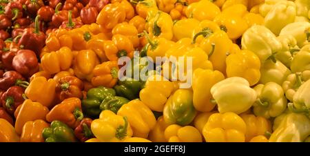Peperoni freschi gialli, verdi, arancioni e rossi in vendita sul mercato alimentare Foto Stock