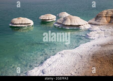I camini di sale sulla riva del Mar Morto formano dove l'acqua fresca fluisce nell'acqua salina del lago e sono esposti come il livello dell'acqua scende. Foto Stock