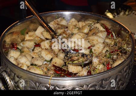 Idli fritto in una grande pentola è decorato con spezie fritte. Foto Stock